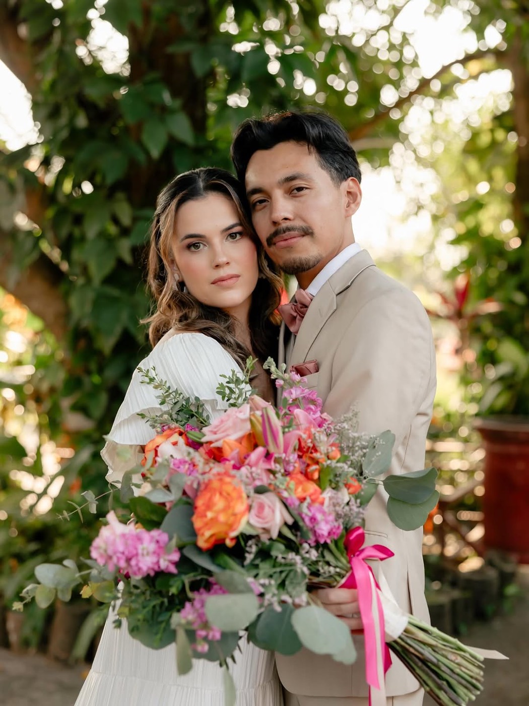 Pareja de novios con ramo de flores en jardín tropical