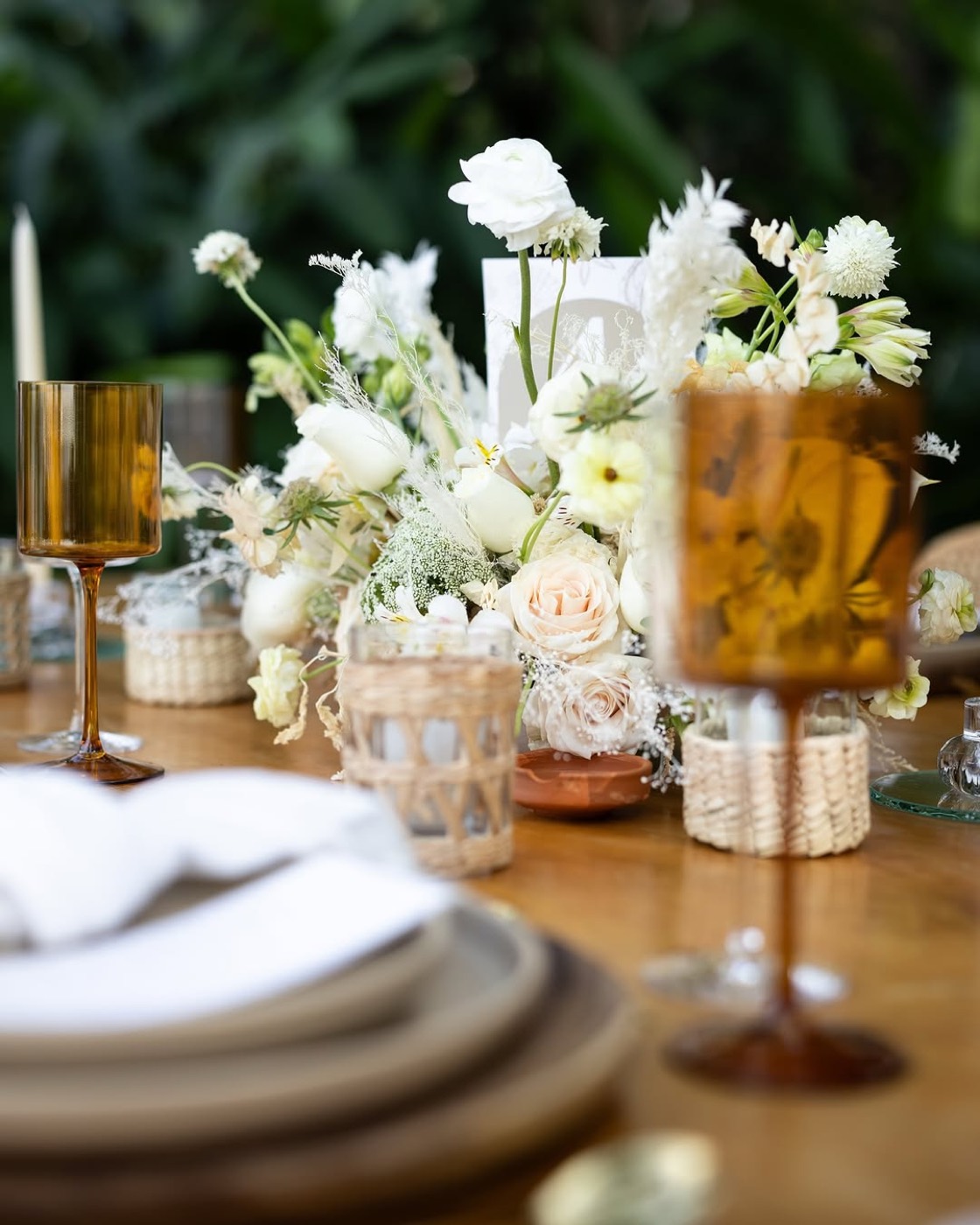 Copas ámbar y flores blancas sobre mesa de madera