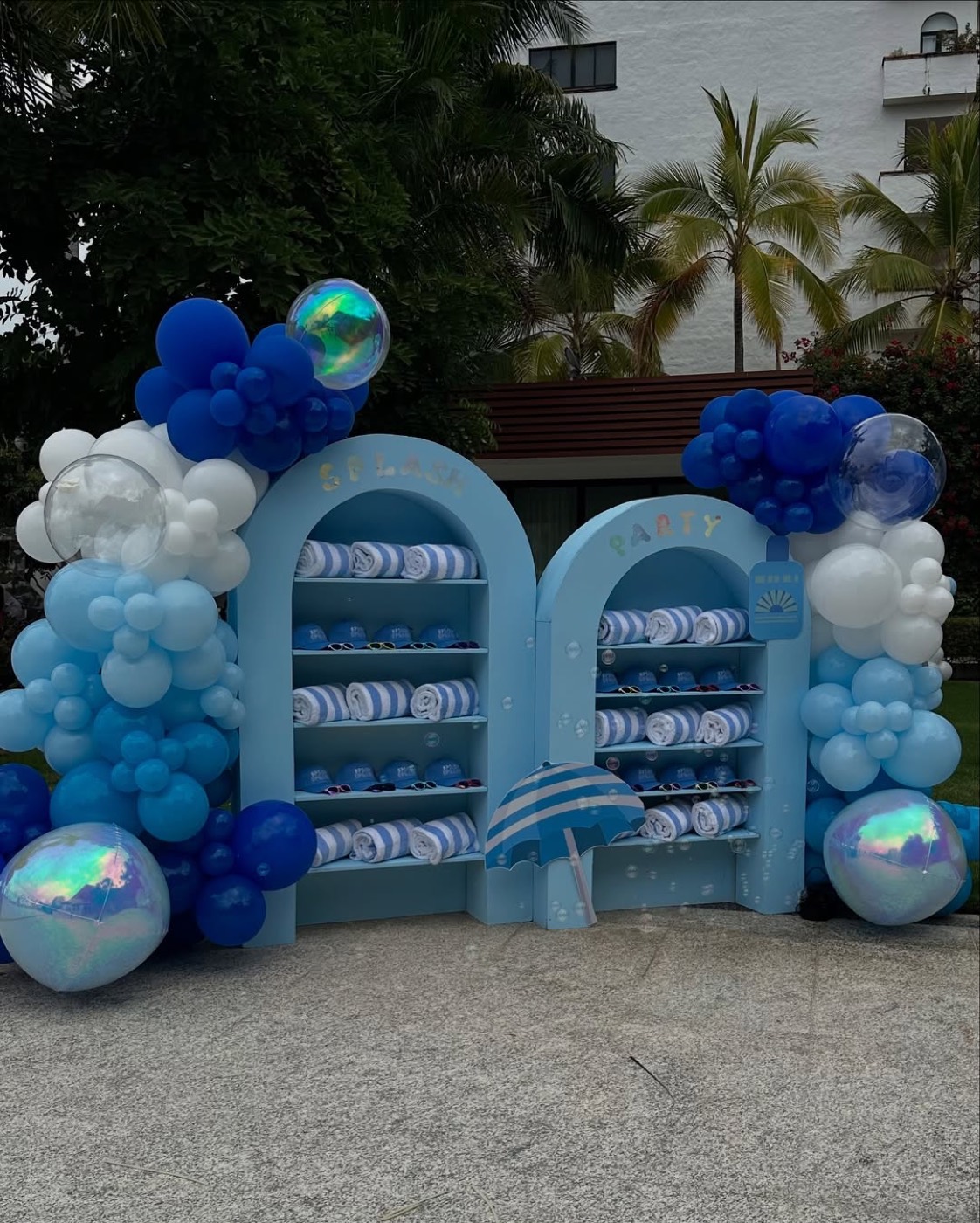Montaje de fiesta con arcos azules, globos y toallas de playa