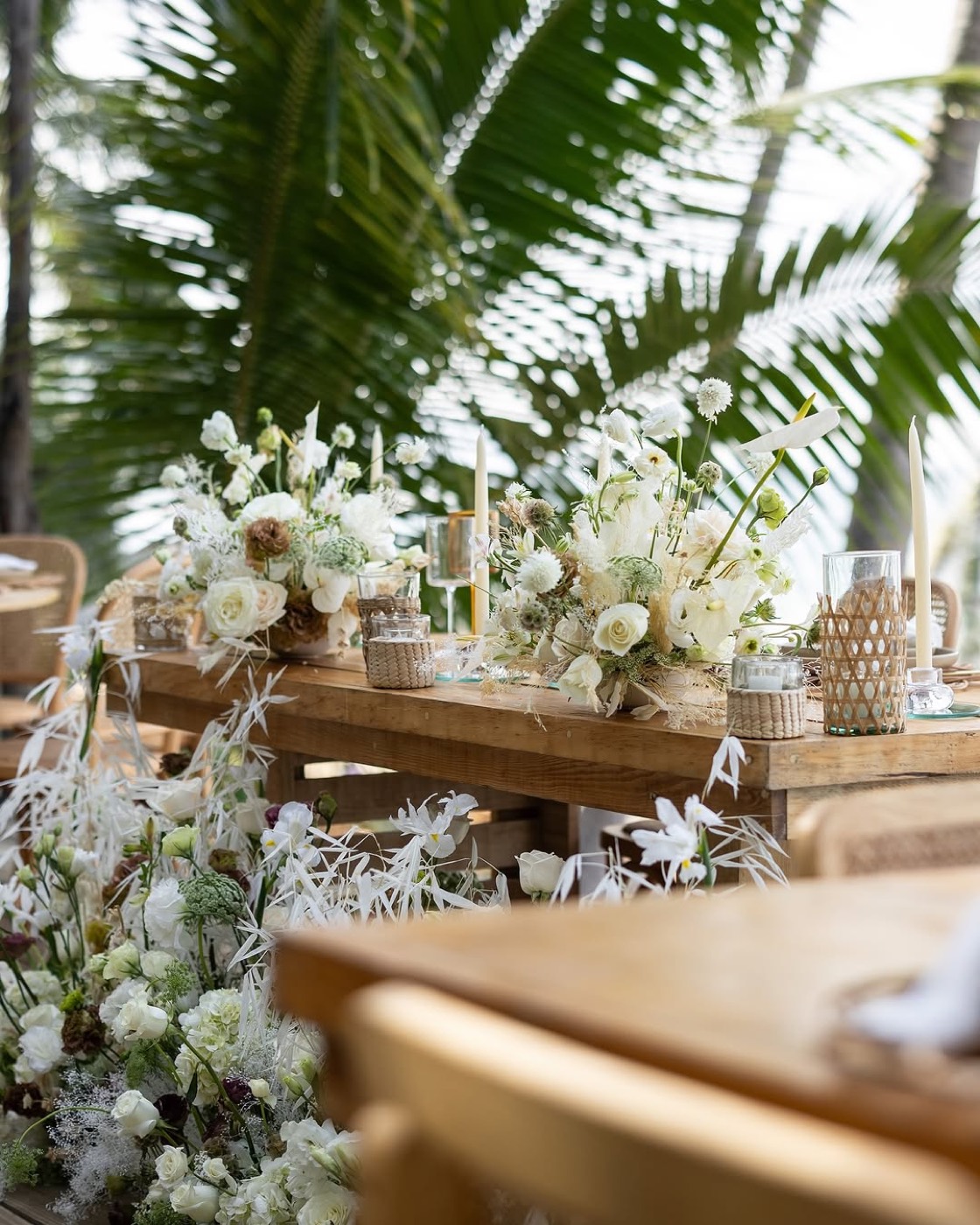 Mesa de boda en la playa con flores blancas y palmeras