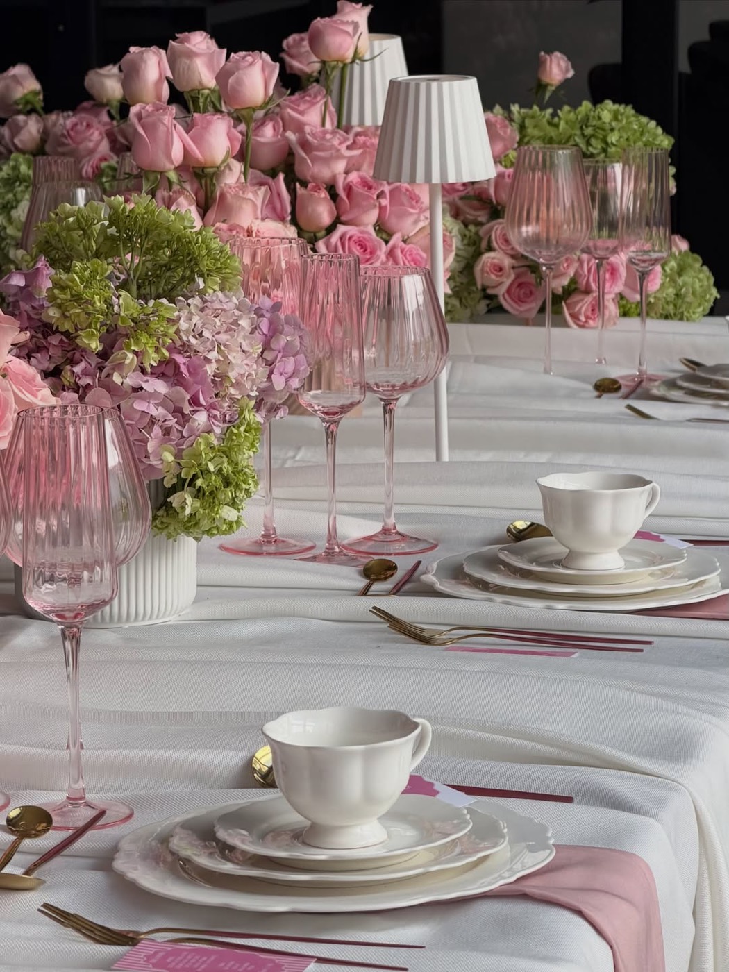Mesa con rosas rosadas, hortensias y cristalería rosa